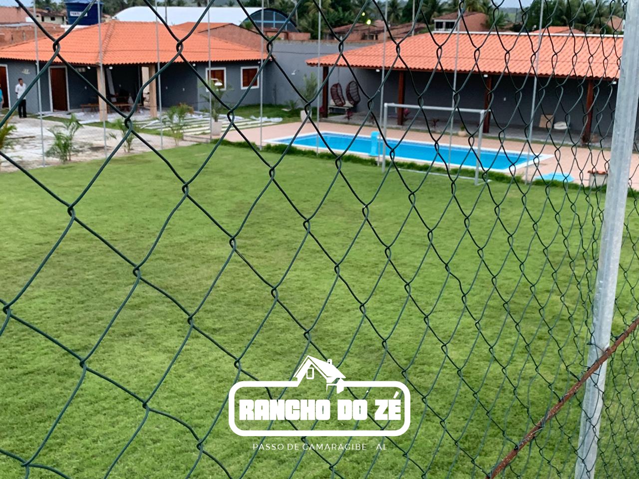 Campo gramado, piscina e chalés de telhado vermelho do Rancho do Zé