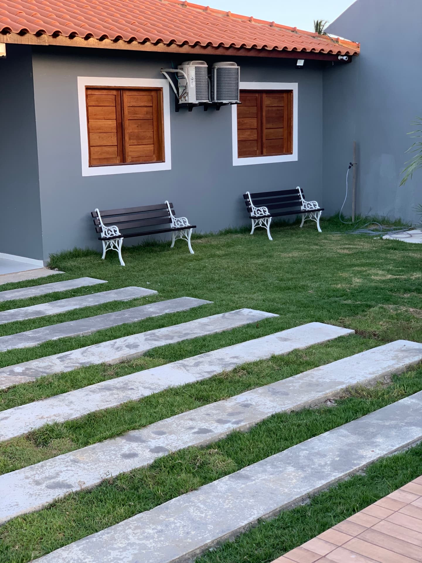 Chalés com janelas de madeira, bancos e caminho de pedra no gramado